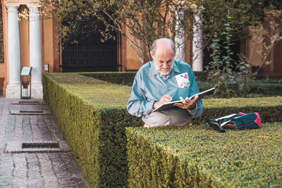 Full length of man sitting on mobile phone in grass