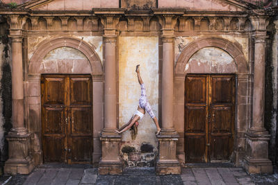 Woman practicing yoga on architectural columns of old building