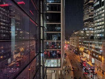 Illuminated city street by buildings at night