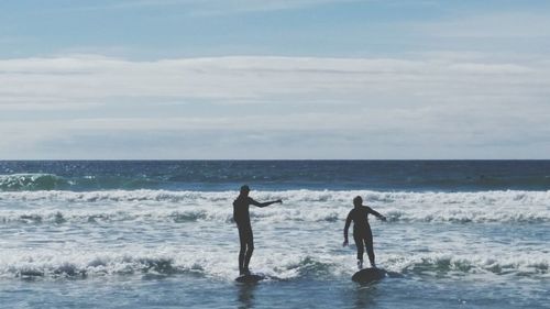 Silhouette people enjoying on beach against sky