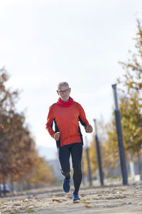 Senior man running on road during autumn