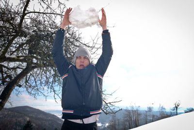 Man making face while throwing big snowball during winter outdoors