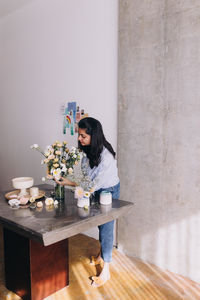 Side view of indian ethnicity florist creating a bouquet of flowers in pastel colors