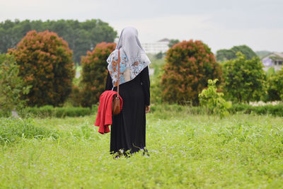 Rear view of woman in hijab standing on field 