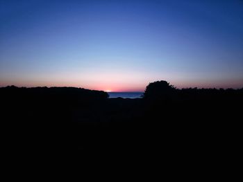 Silhouette landscape against clear sky at sunset