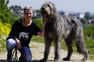 Portrait of mature woman with irish wolfhound on footpath during sunny day
