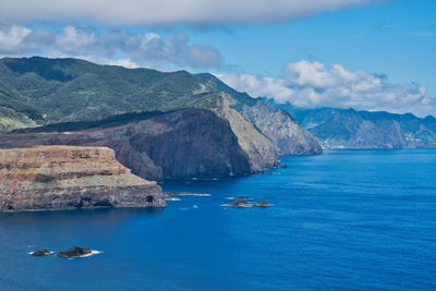 Scenic view of sea by mountains against sky