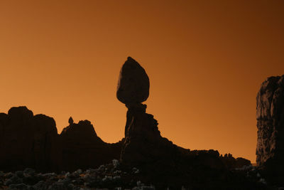 Silhouette rocks in desert against clear sky during sunset