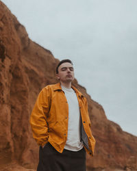 Young man standing against mountain