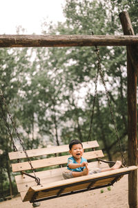 Portrait of boy sitting on swing at playground