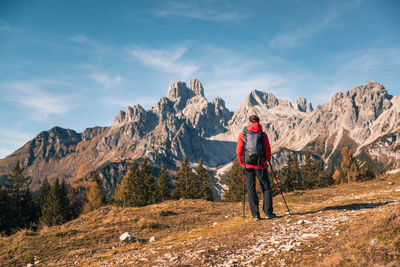 Rear view of woman hiking in forest against sky during winter