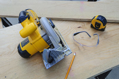 High angle view of carpenter tools on plank at workshop