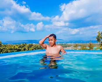 Shirtless man standing in water against sky