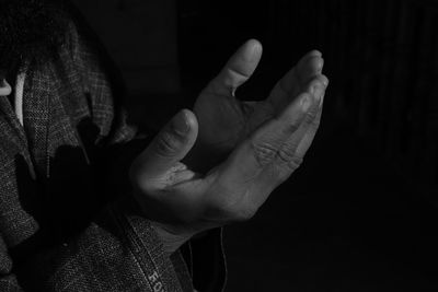 Midsection of man praying against black background