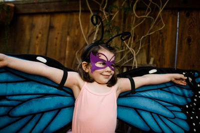 Young girl in dress up spreading butterfly wings