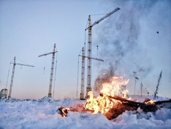 Bonfire on snow covered land against sky