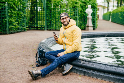 Young man using mobile phone while sitting outdoors