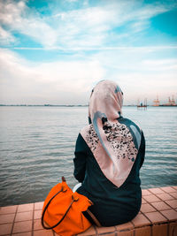 Man sitting on boat in sea against sky