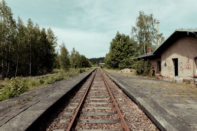 Diminishing perspective of railroad track against cloudy sky