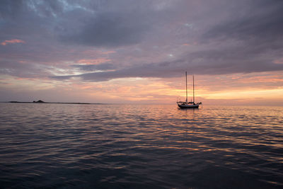 Boat sailing in sea against cloudy sky