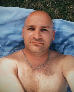 Directly above shot of shirtless man lying on picnic blanket at park