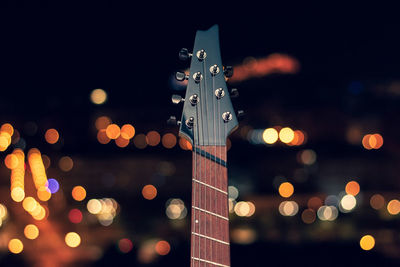 Close-up of guitar against illuminated lights