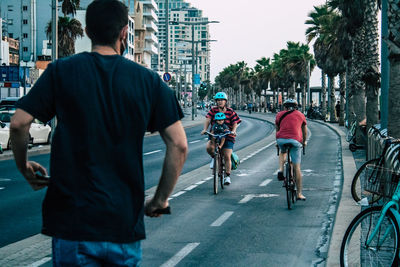 Rear view of people riding bicycle on road