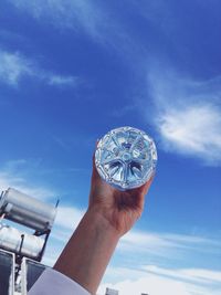 Low angle view of person holding umbrella against blue sky