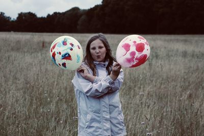 Portrait of a girl holding balloons on field