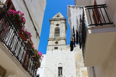 Low angle view of cross amidst buildings against sky