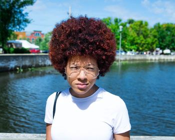 Portrait of smiling young woman against river