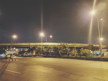 Illuminated street against sky at night