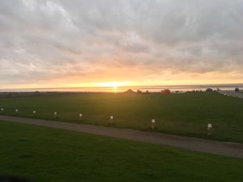 Scenic view of grassy field against sky during sunset