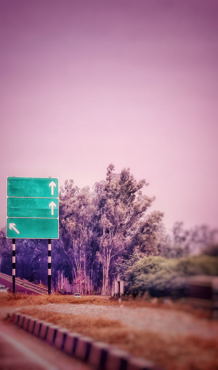 ROAD SIGN BY TREES AGAINST CLEAR SKY