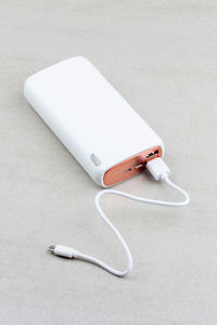 White power bank for charging smartphones and various digital devices on a grey background close-up