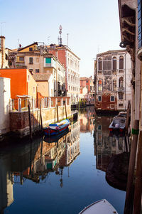 Boats moored in canal against buildings in city