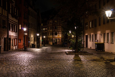 Illuminated street amidst buildings at night