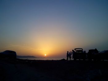 Silhouette people walking on landscape against clear sky during sunset