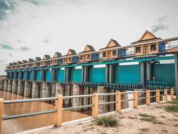 Built structure on beach by houses against sky