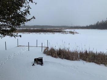 Scenic view of snow covered field by lake against sky