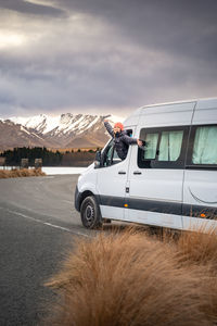 Asian women pose with her camper van for road trip vacation at new zealand south island.