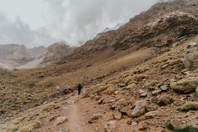 Full length of man standing on field against mountain range and sky