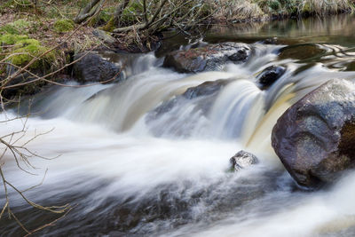 Blurred motion of water flowing amidst rocks in river