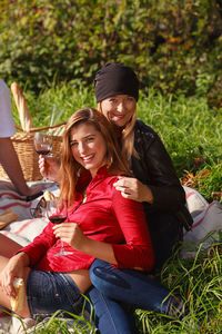 Portrait of smiling female friends sitting on grassy land in park