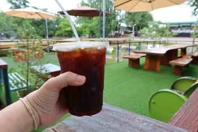 Cropped image of person holding drink on table