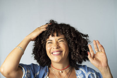 Portrait of smiling beautiful curly hair model against light background. 