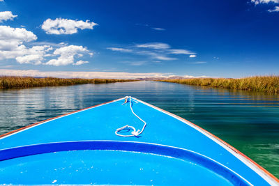 Cropped image of boat on canal against blue sky