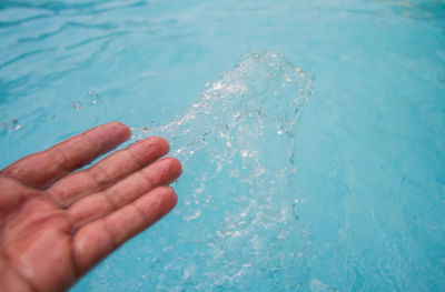 Close-up of hand against blue water