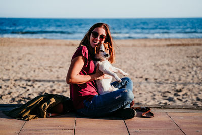 Woman sitting on beach by sea against sky