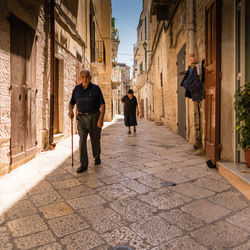 Senior couple walking on footpath amidst buildings